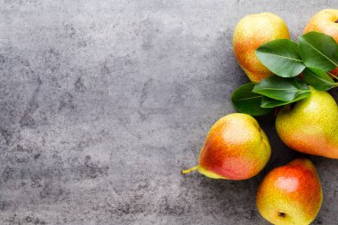 Tabağında yapraklar olan taze bir armut. Gri taş masa.