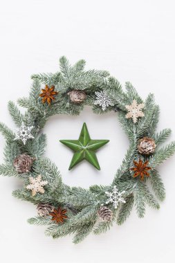 Noel tebrik kartı. Beyaz ahşap arka planda çelenk süsü. Yeni yıl konsepti. Uzayı kopyala Düz yatıyordu. Üst görünüm.