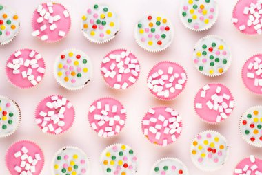 Beyaz arka planda çok renkli, güzel dekore edilmiş muffinler..