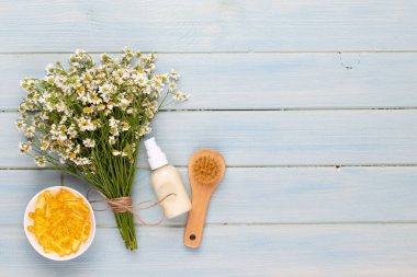 Spa aromaterapi arka planı, sade papatya çiçekleriyle süslenmiş çeşitli güzellik ürünleri..