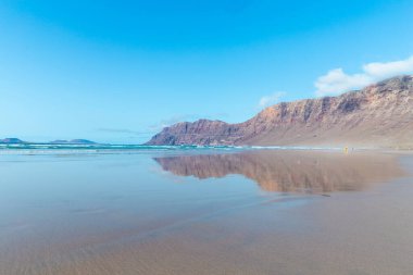 Güzel sahil manzarası ve tropikal Lanzarote denizi. Kanaryalar. Famara Sahili, Lanzarote Adası, Kanarya Adaları. Lanzarote adasındaki en popüler plajda turistler.