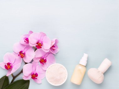 Spa aromaterapi arka planı, basit orkide çiçekleriyle süslenmiş çeşitli güzellik ürünleri..
