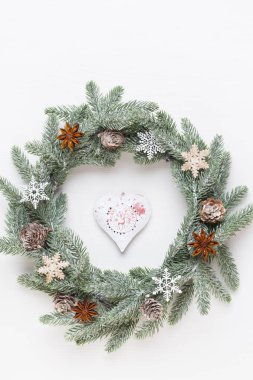 Noel tebrik kartı. Beyaz ahşap arka planda çelenk süsü. Yeni yıl konsepti. Uzayı kopyala Düz yatıyordu. Üst görünüm.