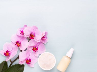 Spa aromaterapi arka planı, basit orkide çiçekleriyle süslenmiş çeşitli güzellik ürünleri..