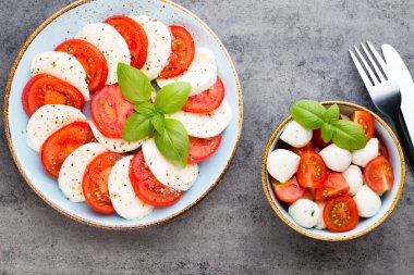 Domates, mozzarella peyniri, fesleğen ve baharatlar gri tahtada. İtalyan geleneksel Caprese salata malzemeleri. Akdeniz yemekleri.