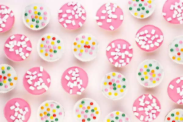 Beyaz arka planda çok renkli, güzel dekore edilmiş muffinler..