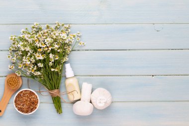 Spa aromaterapi arka planı, sade papatya çiçekleriyle süslenmiş çeşitli güzellik ürünleri..