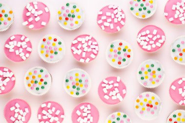 Beyaz arka planda çok renkli, güzel dekore edilmiş muffinler..