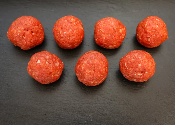 karanlık bazalt plaka arka plan üzerinde kırmızı biber ile parlak çiğ köfte