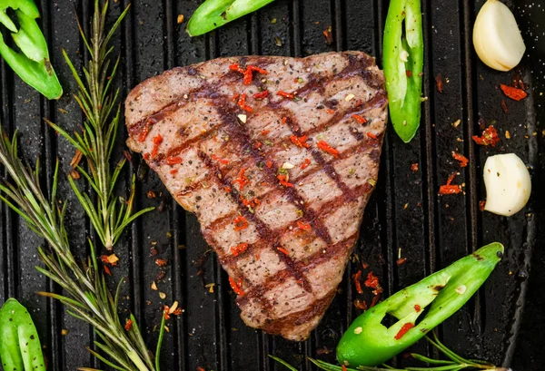 Bife assado em uma frigideira com alecrim, alho e pimenta verde . — Fotografia de Stock