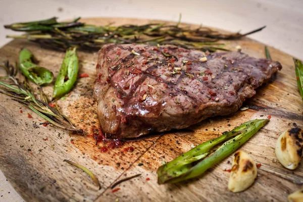Carne assada em uma tábua de cortar com alecrim e pimenta verde . — Fotografia de Stock
