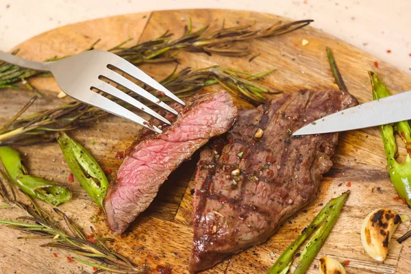 Saftigt medium nötkött RIB Eye Steak skivor på trä kartong med gaffel och kniv. — Stockfoto