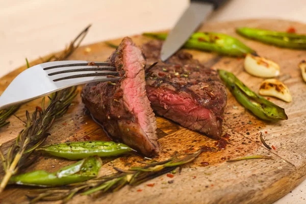 Saftigt medium nötkött RIB Eye Steak skivor på trä kartong med gaffel och kniv. — Stockfoto