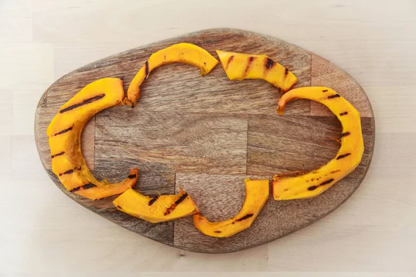 Grilled pumpkin pieces lie on a wooden Board.