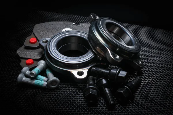 Auto parts on a black background. brake pads, bearings, fasteners. Black metal mesh background