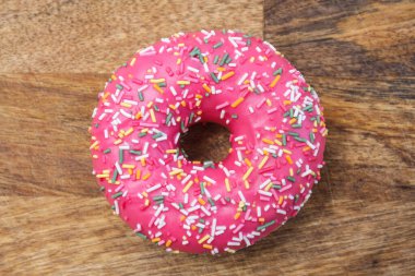 Ahşap zemine serpiştirilmiş pembe donut.