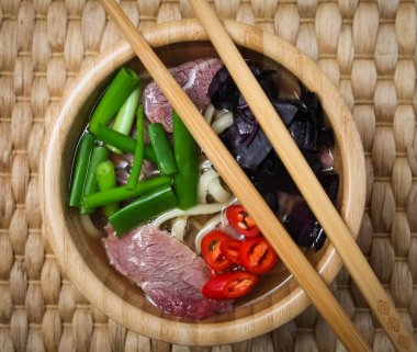 Vietnam usulü Pho Bo çorbası, biftek ve bambu kasesinde taze fesleğen.