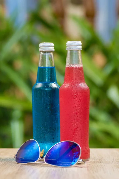 Bottles a with colorful drinks  stand on a table on a green background