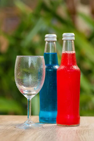 Bottles a with colorful drinks  stand on a table on a green background