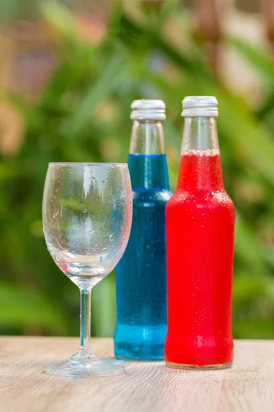 Bottles a with colorful drinks  stand on a table on a green background