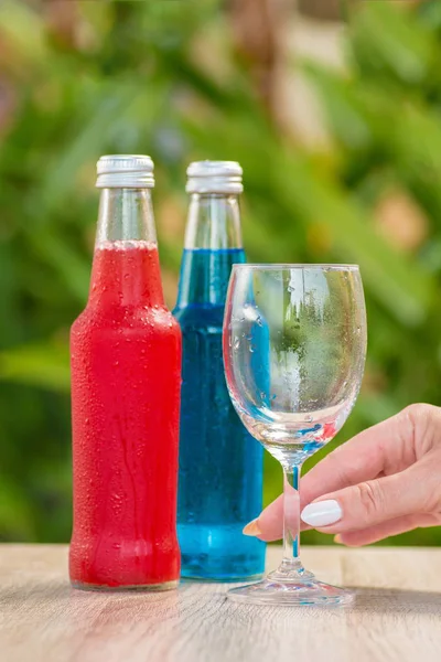 woman with Bottles a with colorful drinks  stand on a table on a green background