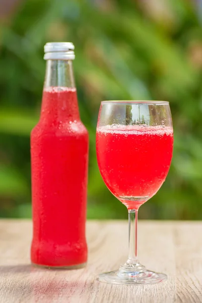 glass and a bottle with drink stand on a table on a green background