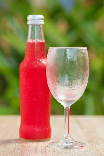 glass and a bottle with drink stand on a table on a green background