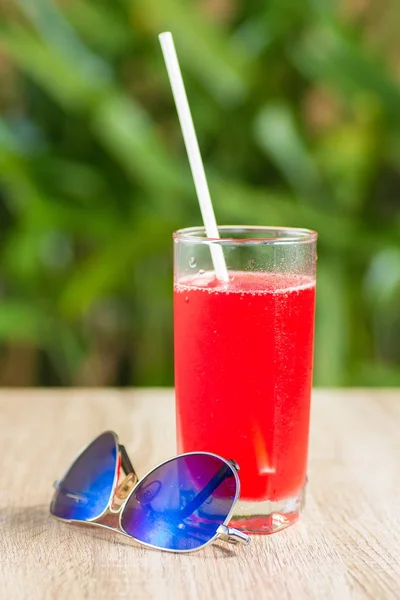 glass with red drink stand on a table on a green background