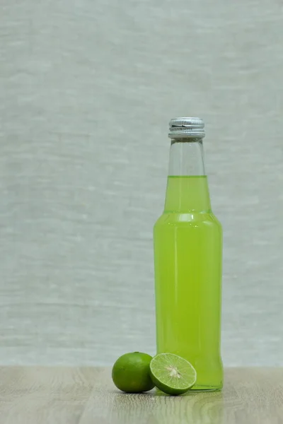Bottle with  drink  and limes on background