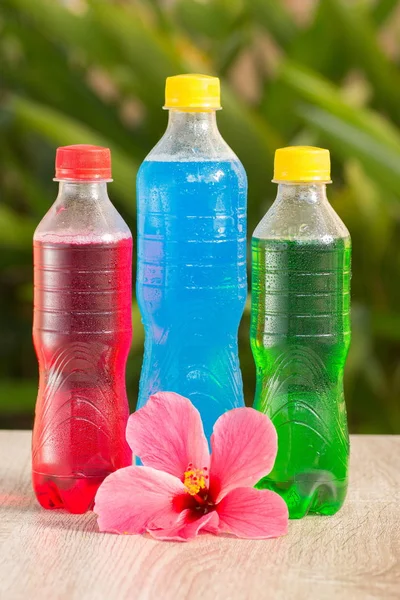 Bottles a with colorful drinks  stand on a table on a green background