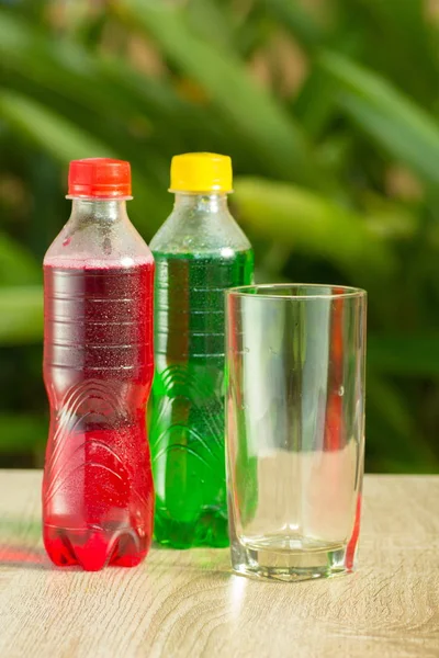 Bottles a with colorful drinks  stand on a table on a green background