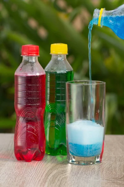 Bottles a with colorful drinks  stand on a table on a green background