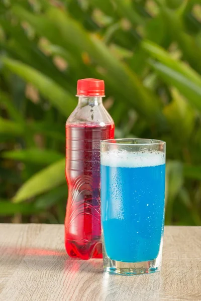 Bottle a with colorful drinks  stand on a table on a green background