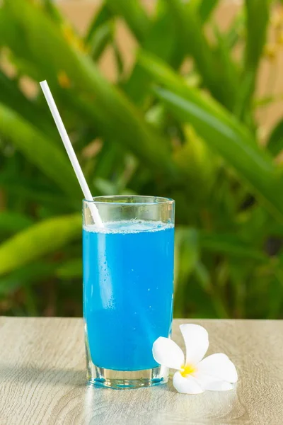 glass with blue drink stand on a table on a green background