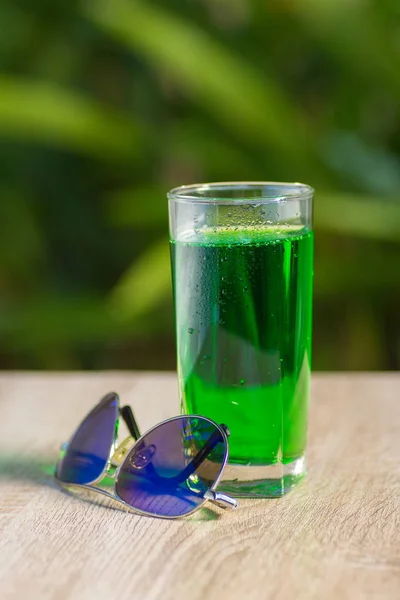 glass with  drink stand on a table on a green background