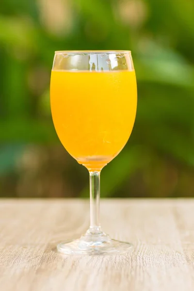 glass with orange drink stand on a table on a green background