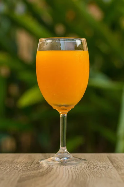 glass with orange drink stand on a table on a green background