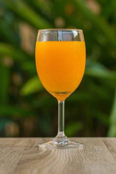 glass with orange drink stand on a table on a green background