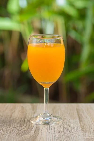 glass with orange drink stand on a table on a green background