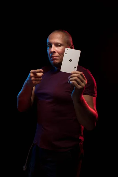 man holds a deck of cards and shows tricks in a scenic light