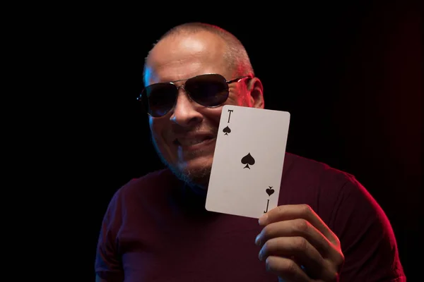 man holds a deck of cards and shows tricks in a scenic light