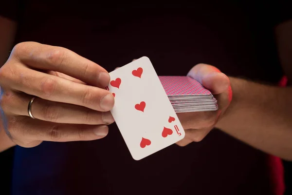 man holds a deck of cards and shows tricks in a scenic light.