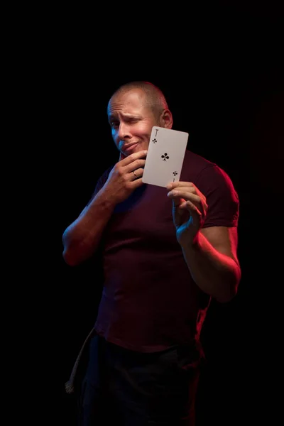 man holds a deck of cards and shows tricks in a scenic light