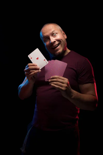 man holds a deck of cards and shows tricks in a scenic light