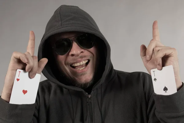 man holds a deck of cards and shows tricks in a scenic light