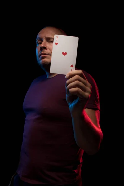 man holds a deck of cards and shows tricks in a scenic light