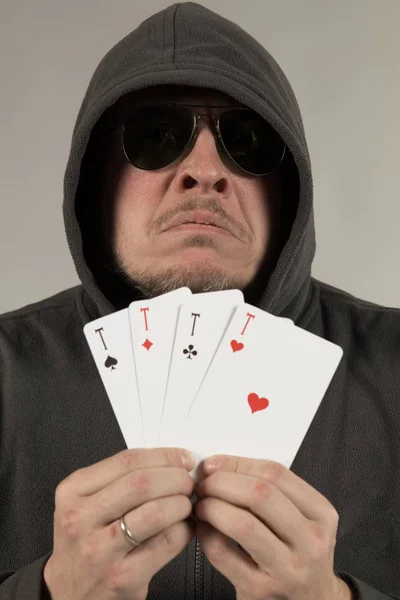 man holds a deck of cards and shows tricks in a scenic light