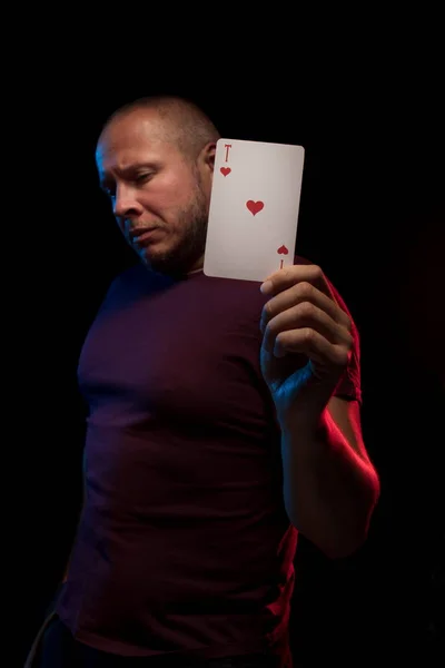 man holds a deck of cards and shows tricks in a scenic light