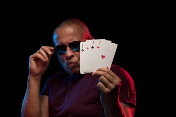 man holds a deck of cards and shows tricks in a scenic light