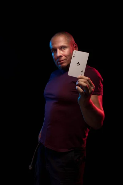 man holds a deck of cards and shows tricks in a scenic light